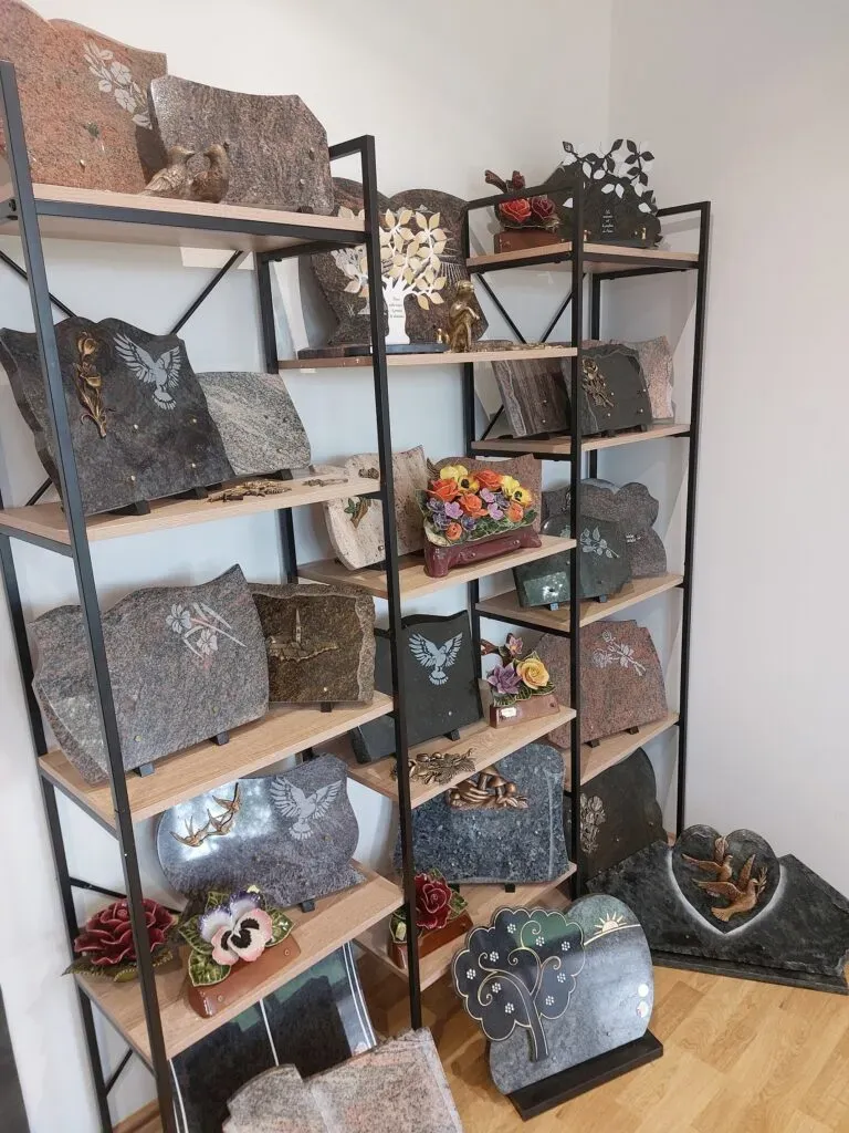 Étagères de présentation remplies de plaques funéraires en pierre et décors.